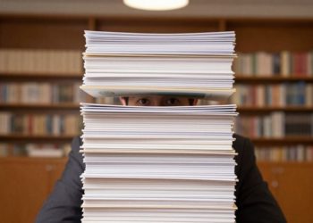 persona escondida detrás de muchos diplomas apilados